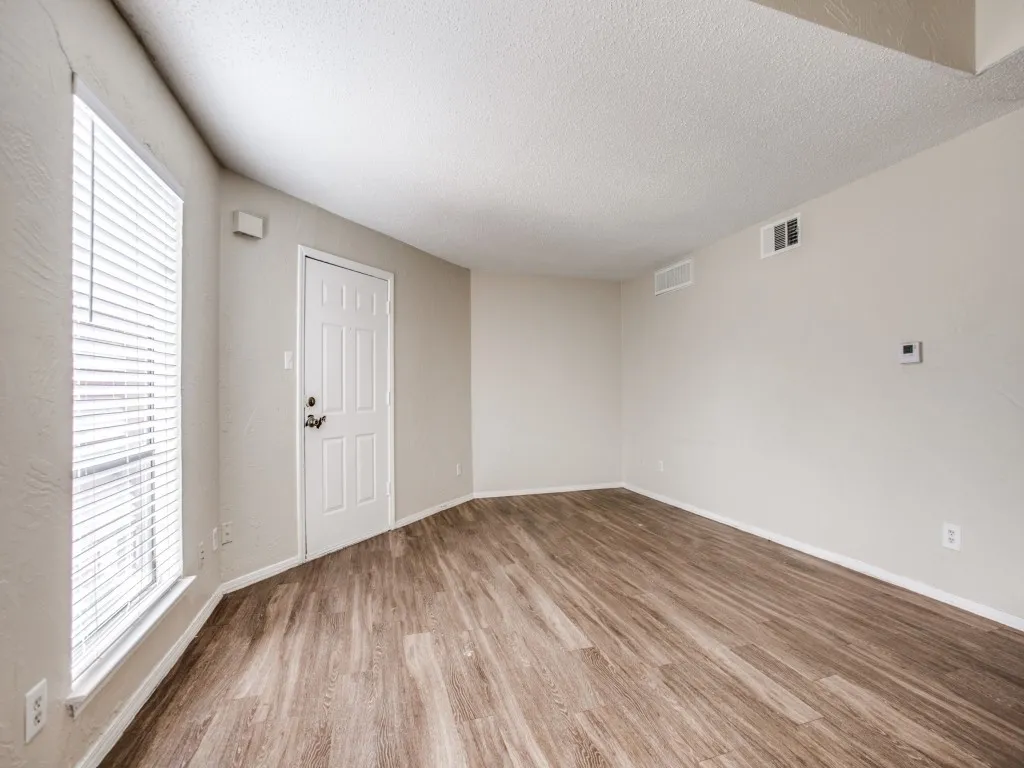 Unfurnished room featuring hardwood / wood-style flooring, plenty of natural light, and a textured ceiling