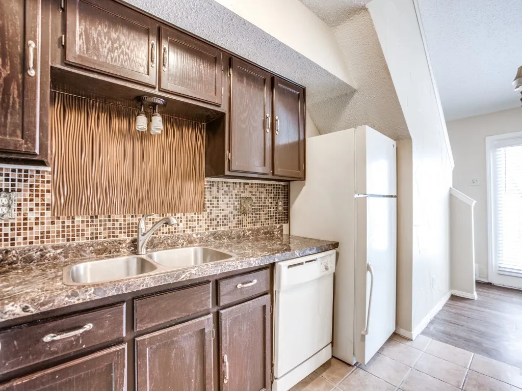 Kitchen with sink, dark brown cabinets, decorative backsplash, white appliances, and light hardwood / wood-style floors