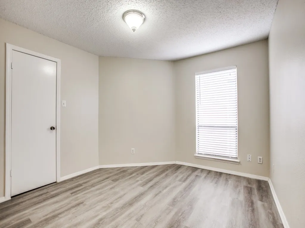 Empty room featuring a textured ceiling and light wood-type flooring