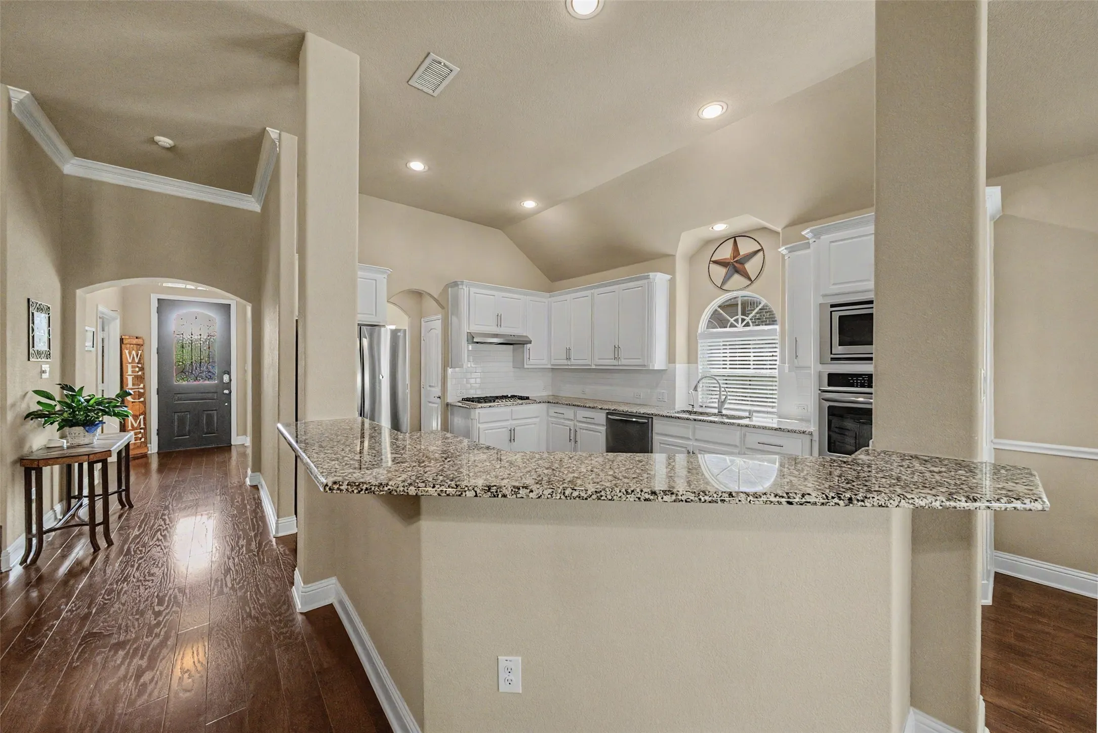 Modern kitchen featuring white cabinetry, a granite countertop island, stainless steel appliances, and a tile backsplash