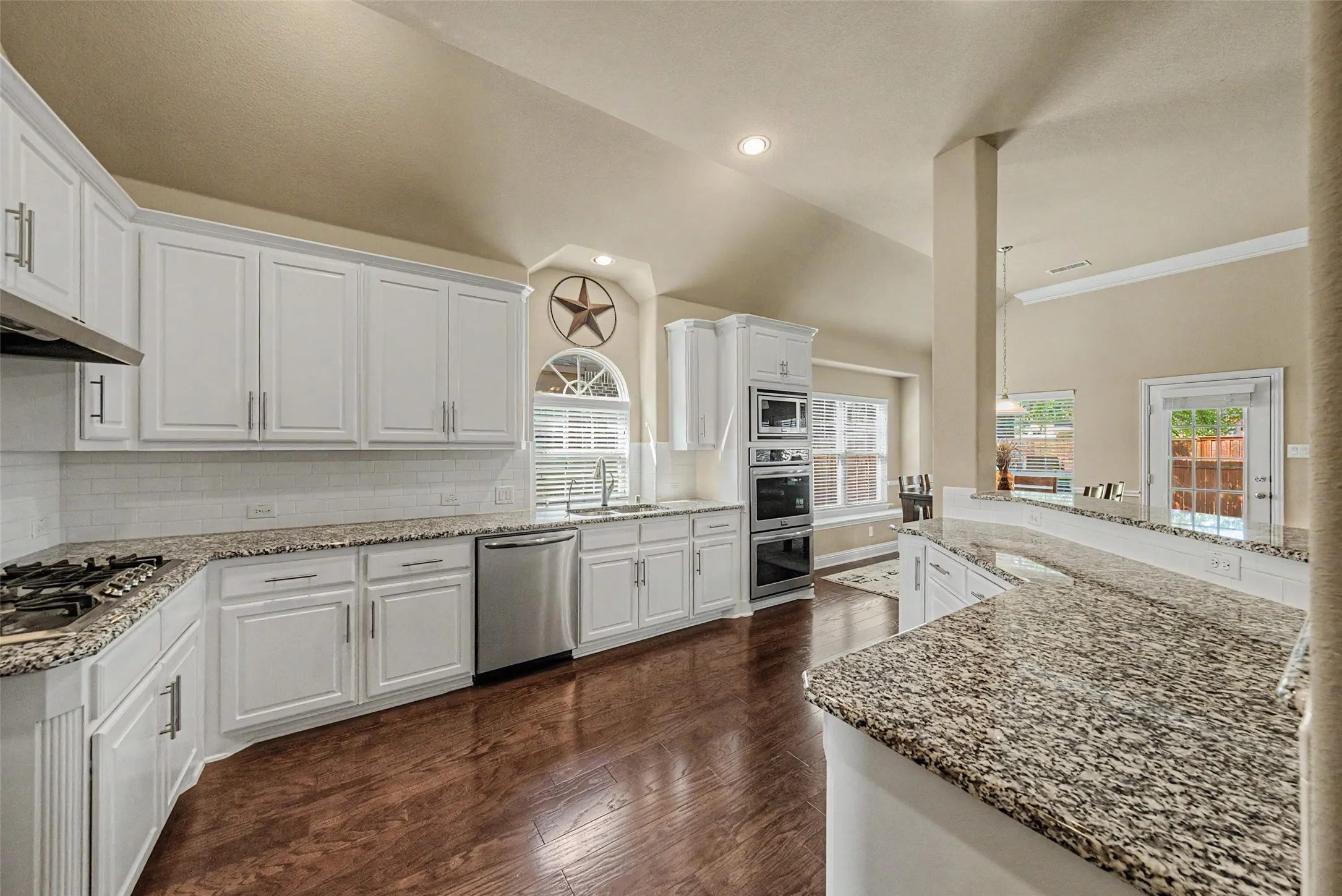 Kitchen featuring white cabinetry, granite countertops, stainless steel appliances, a gas cooktop, and wood-finish flooring