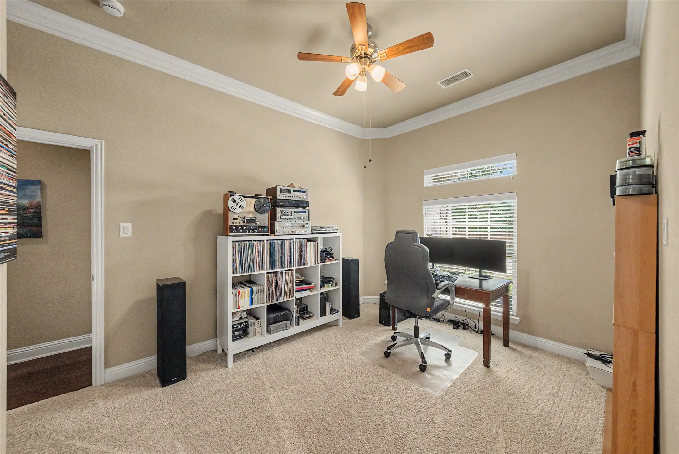 Carpeted room featuring a ceiling fan, crown molding, a window with blinds, and a transom window
