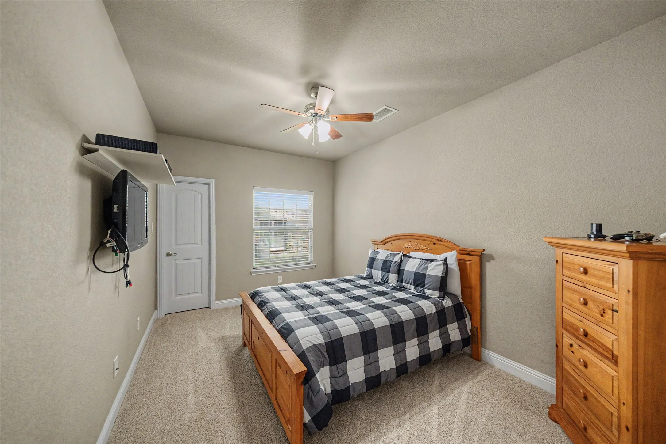 Carpeted room featuring a ceiling fan, a window with blinds, and a paneled door