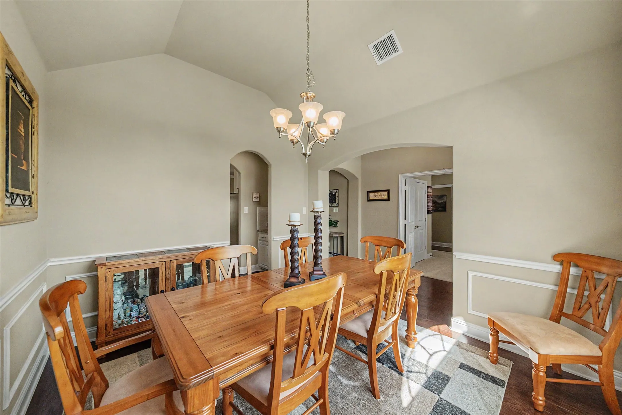 Vaulted ceiling with an elegant chandelier, framed by arched doorways, and featuring wainscoting and crown molding details
