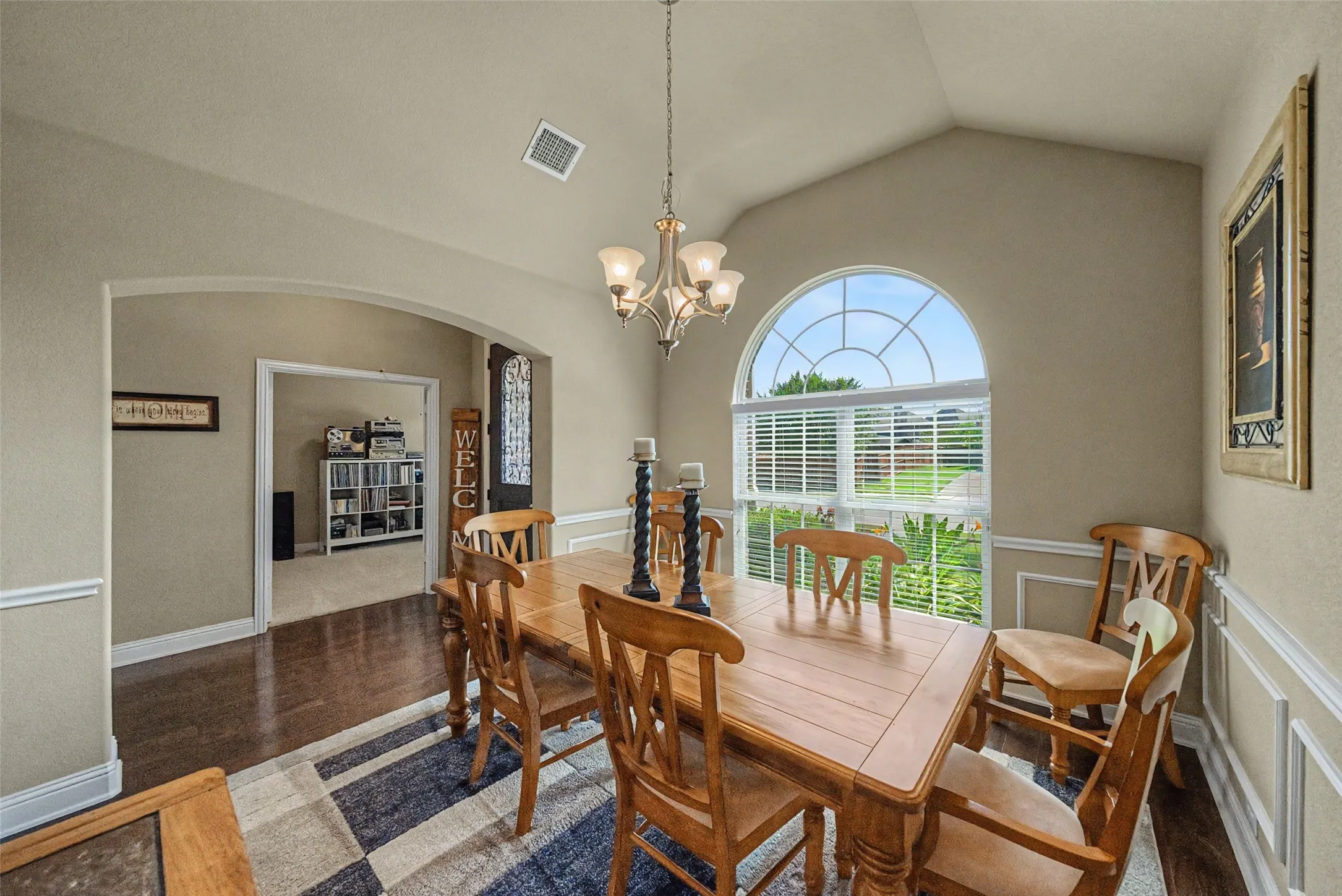 Dining space featuring a vaulted ceiling and an arched window with horizontal blinds