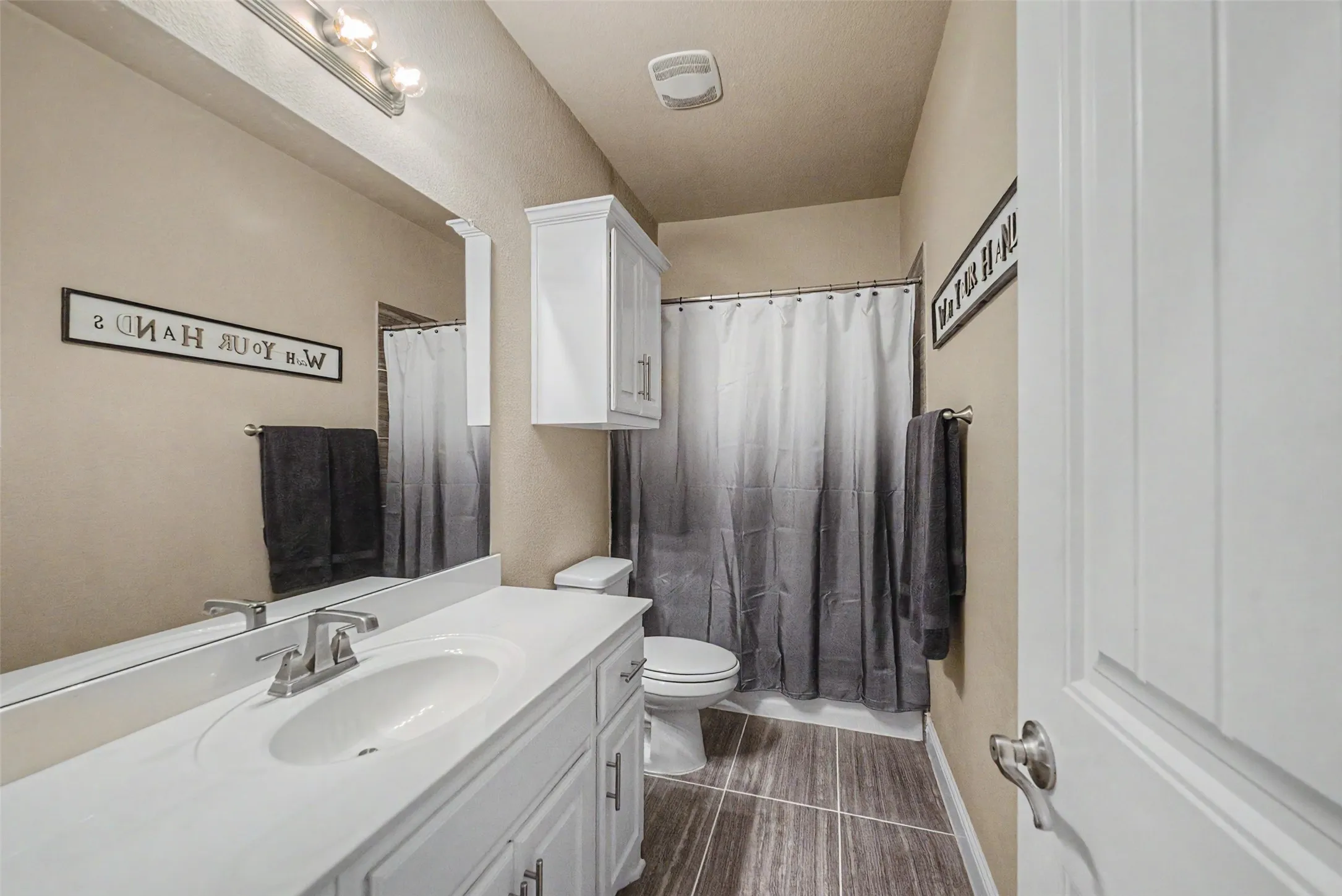 Bathroom featuring a white vanity with an integrated sink, brushed nickel faucet, and a large mirror