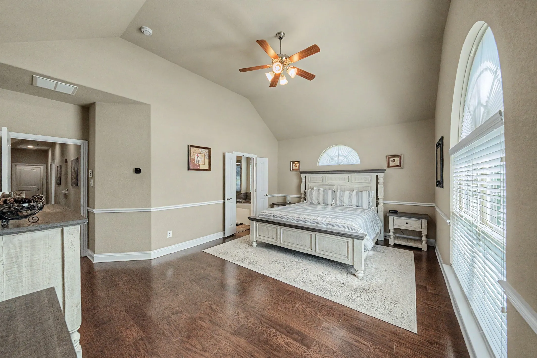 Spacious room featuring vaulted ceilings, wood-finish flooring, and crown molding