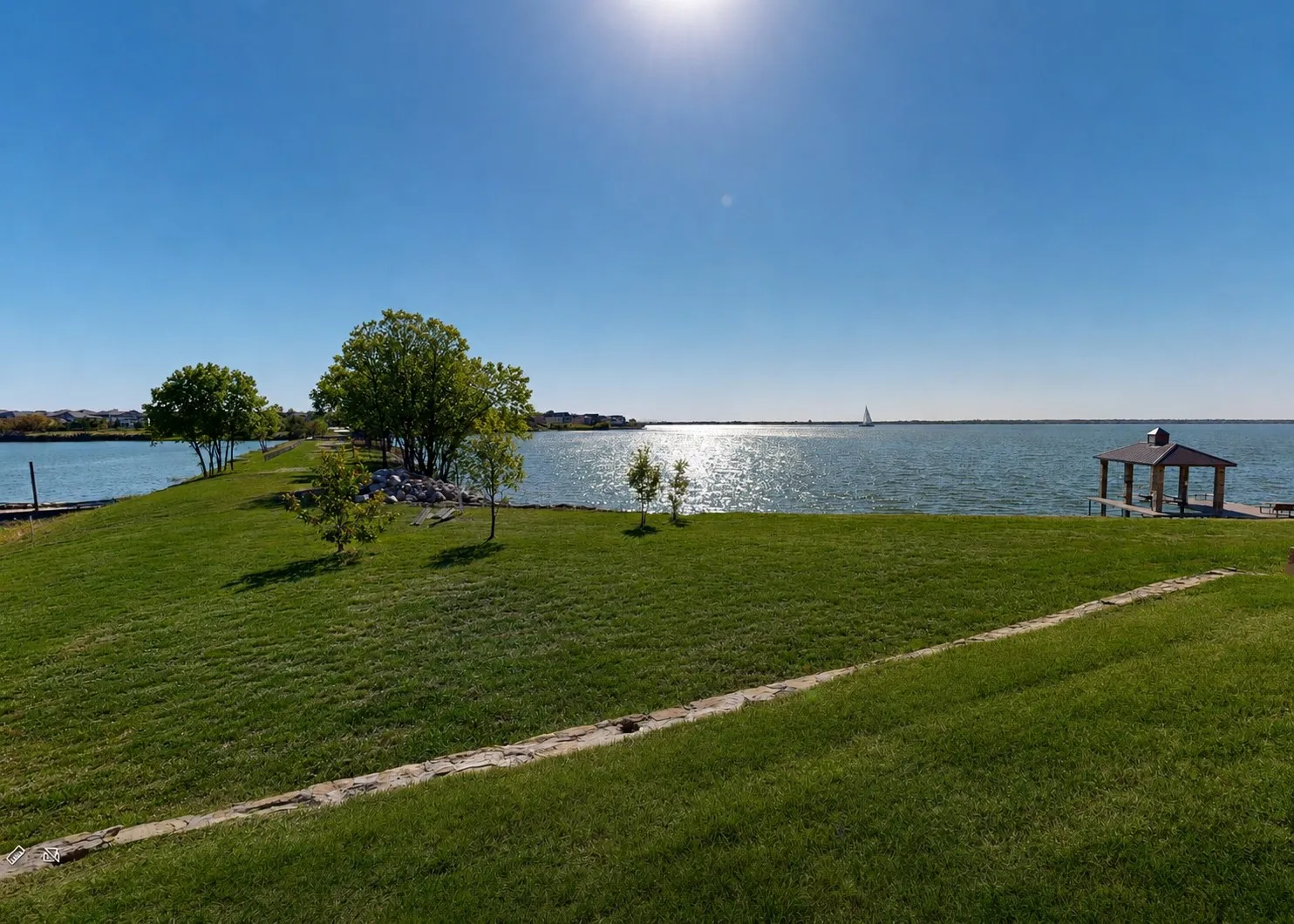 Expansive waterfront property featuring a manicured lawn, established trees, and a private dock with a covered gazebo