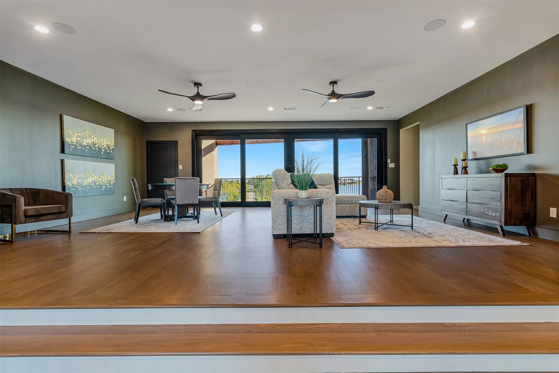 Expansive living area with wood-finish flooring, recessed lighting, and dual ceiling fans