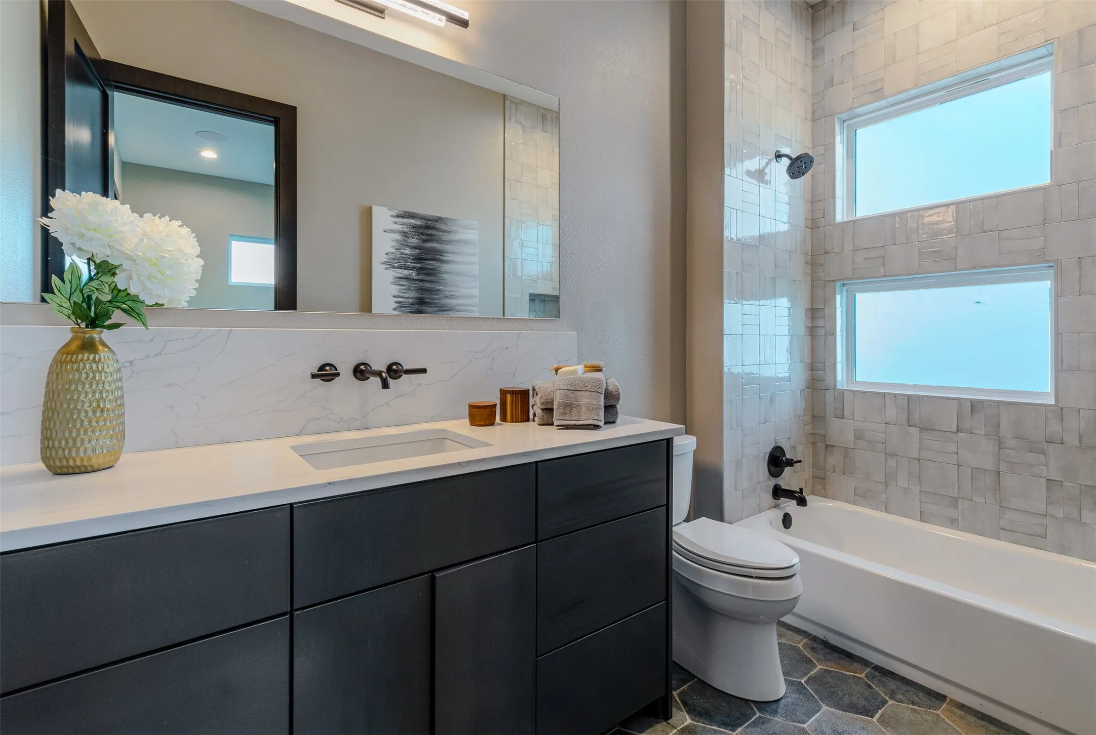 Bathroom featuring a built-in tub with tile surround and two horizontal windows