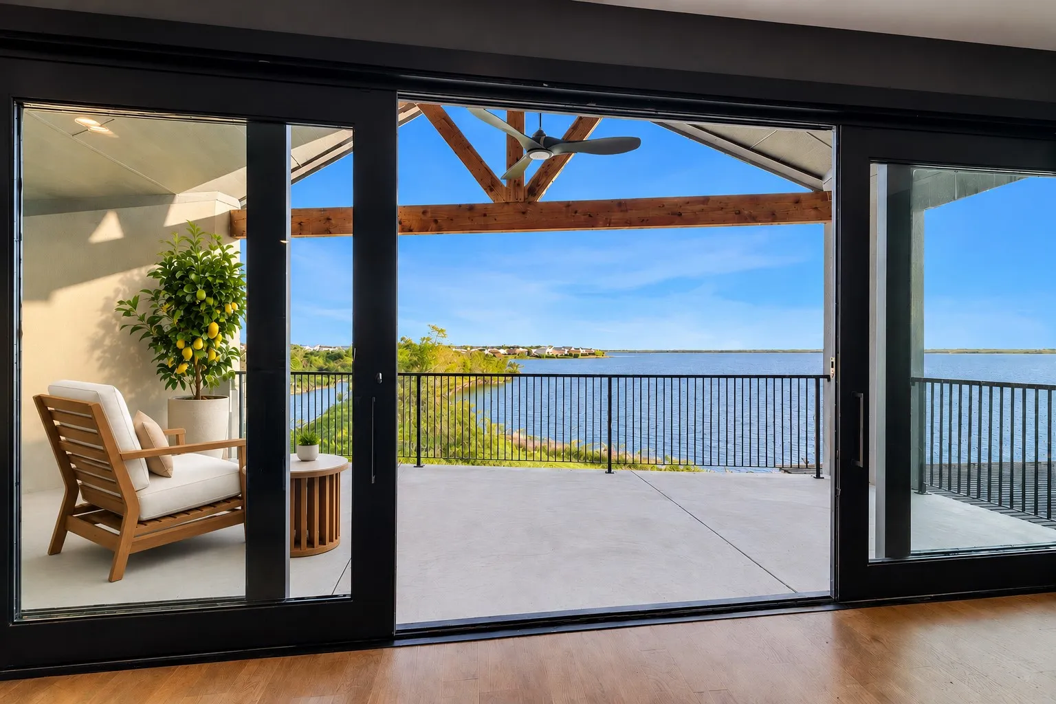 Expansive patio with water frontage, framed by large black-trimmed sliding glass doors