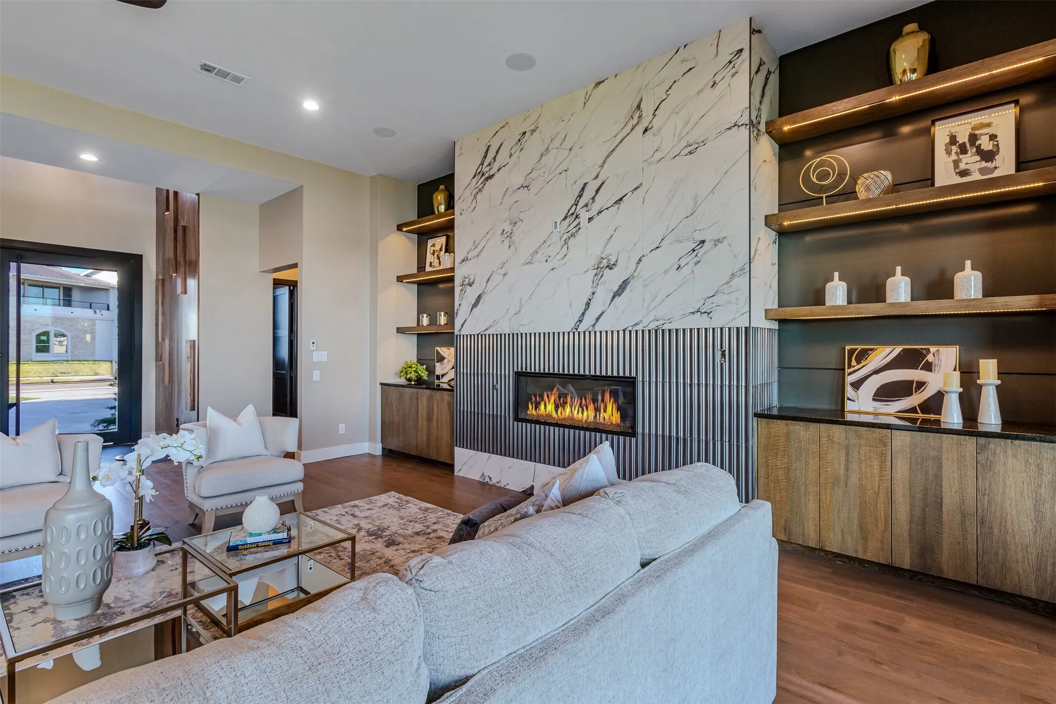 Contemporary living space featuring a linear fireplace with a stone-look surround and fluted paneling