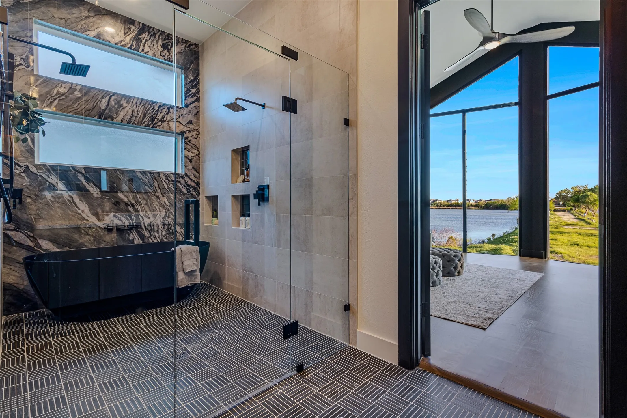 Luxurious bathroom featuring a freestanding soaking tub, large glass-enclosed shower with dual shower heads, and patterned tile flooring