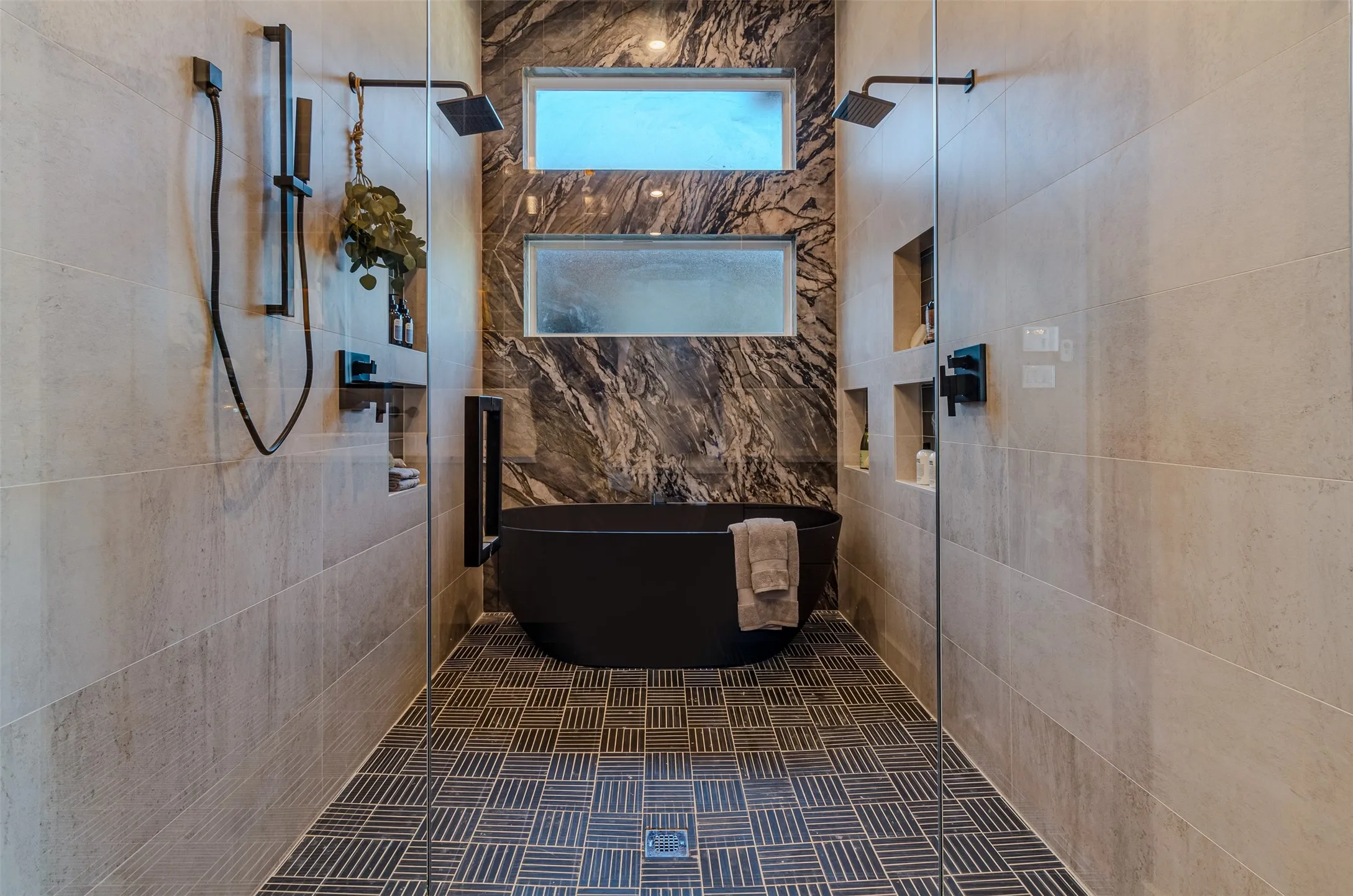 Freestanding matte black soaking tub with a striking marble-finish accent wall