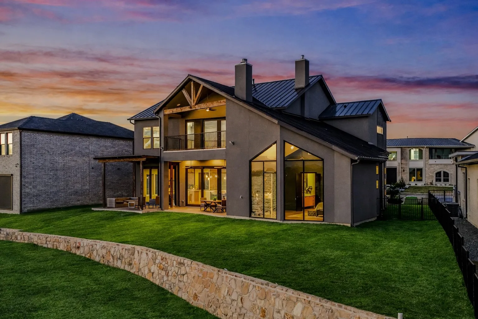Modern architectural design featuring a metal roof, stucco exterior, and striking floor-to-ceiling windows