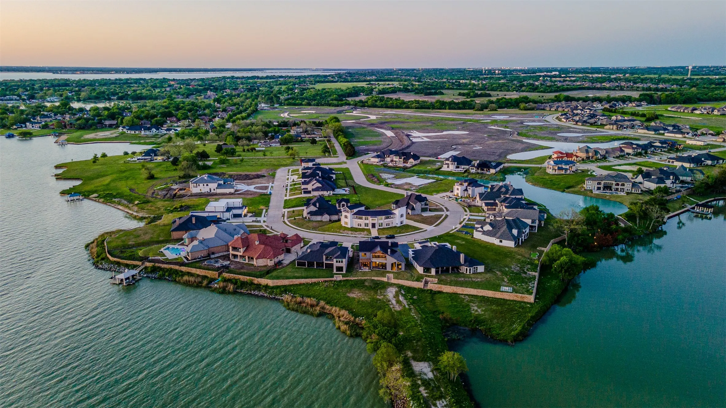 Waterfront community featuring custom homes, a private dock, manicured green spaces, and a circular street layout