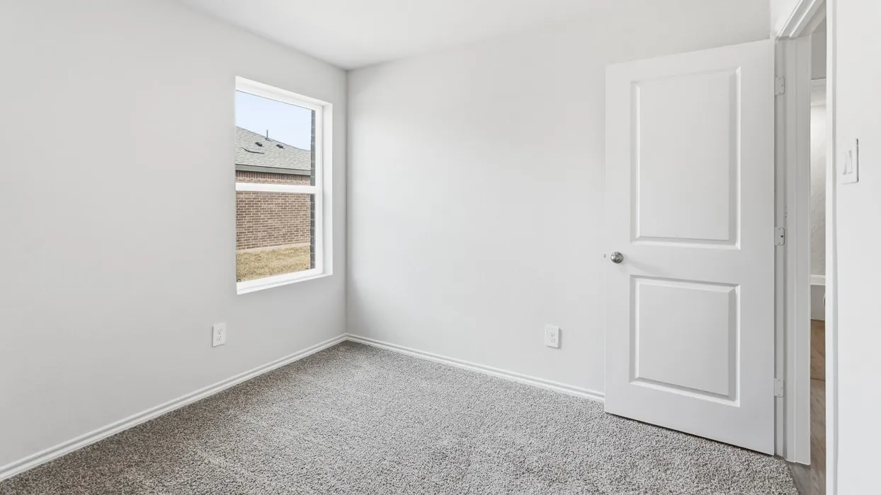 Neutral-toned room featuring light gray walls, plush gray carpeting, and white baseboards