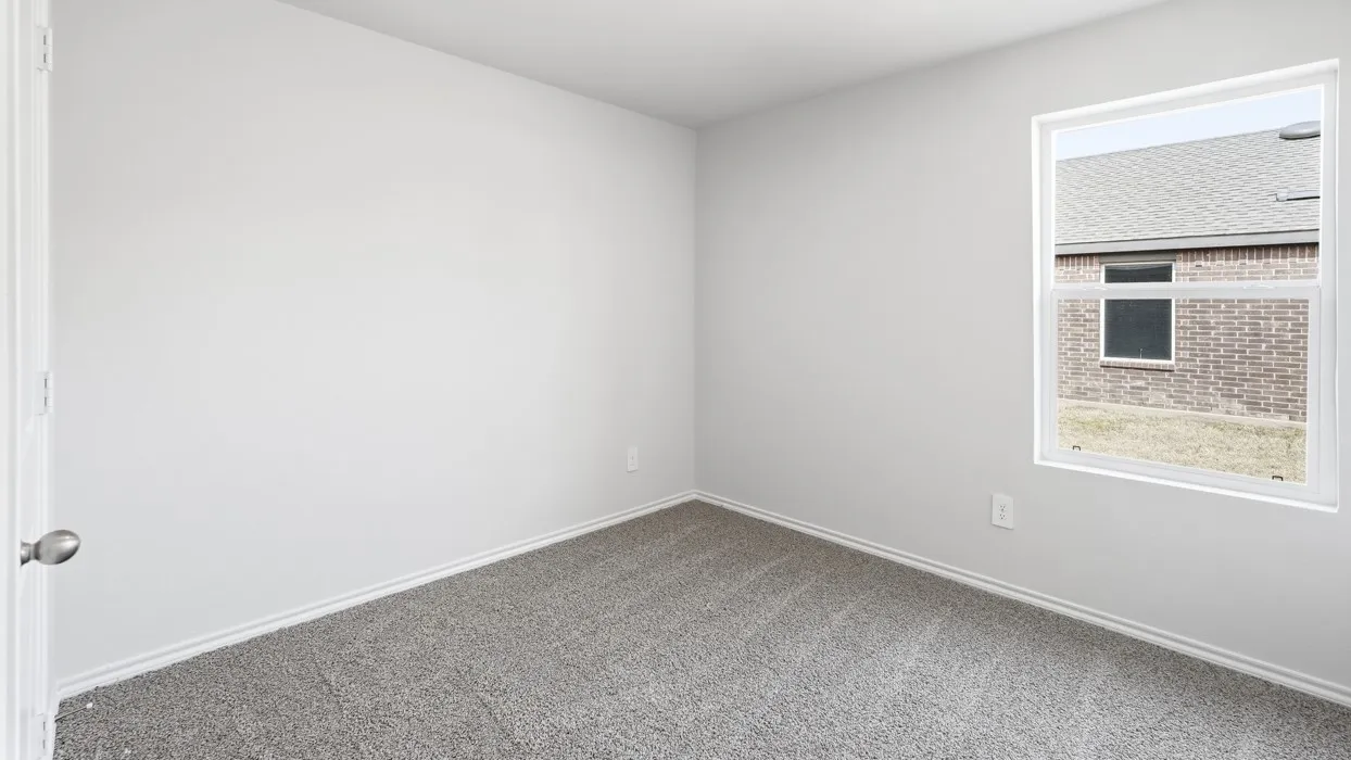 Spacious room featuring neutral paint, gray carpet, a single window, white trim, and a white door with a brushed nickel knob