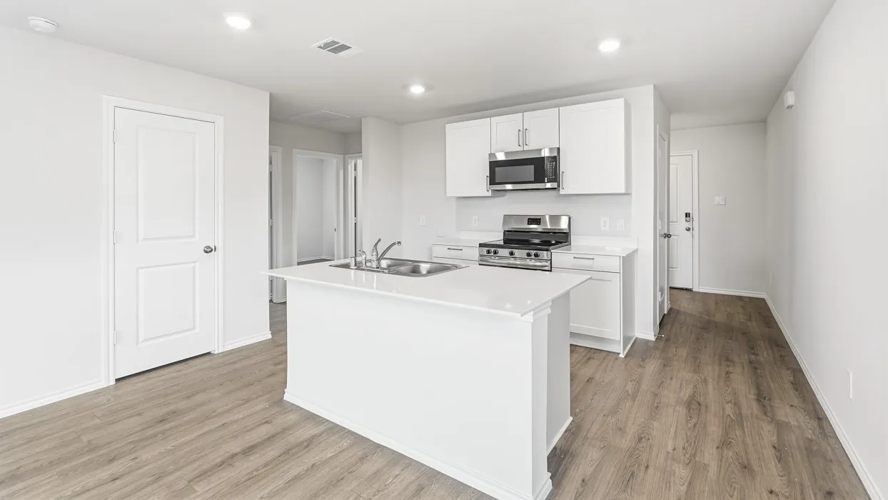 Modern kitchen featuring an island with an integrated double sink, white cabinetry, stainless steel appliances, and wood-finish flooring