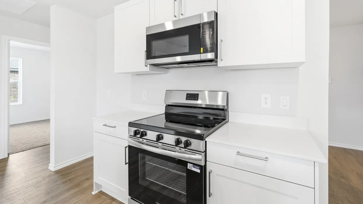 Modern kitchen featuring white cabinetry, light-toned countertops, stainless steel appliances, and wood-finish flooring