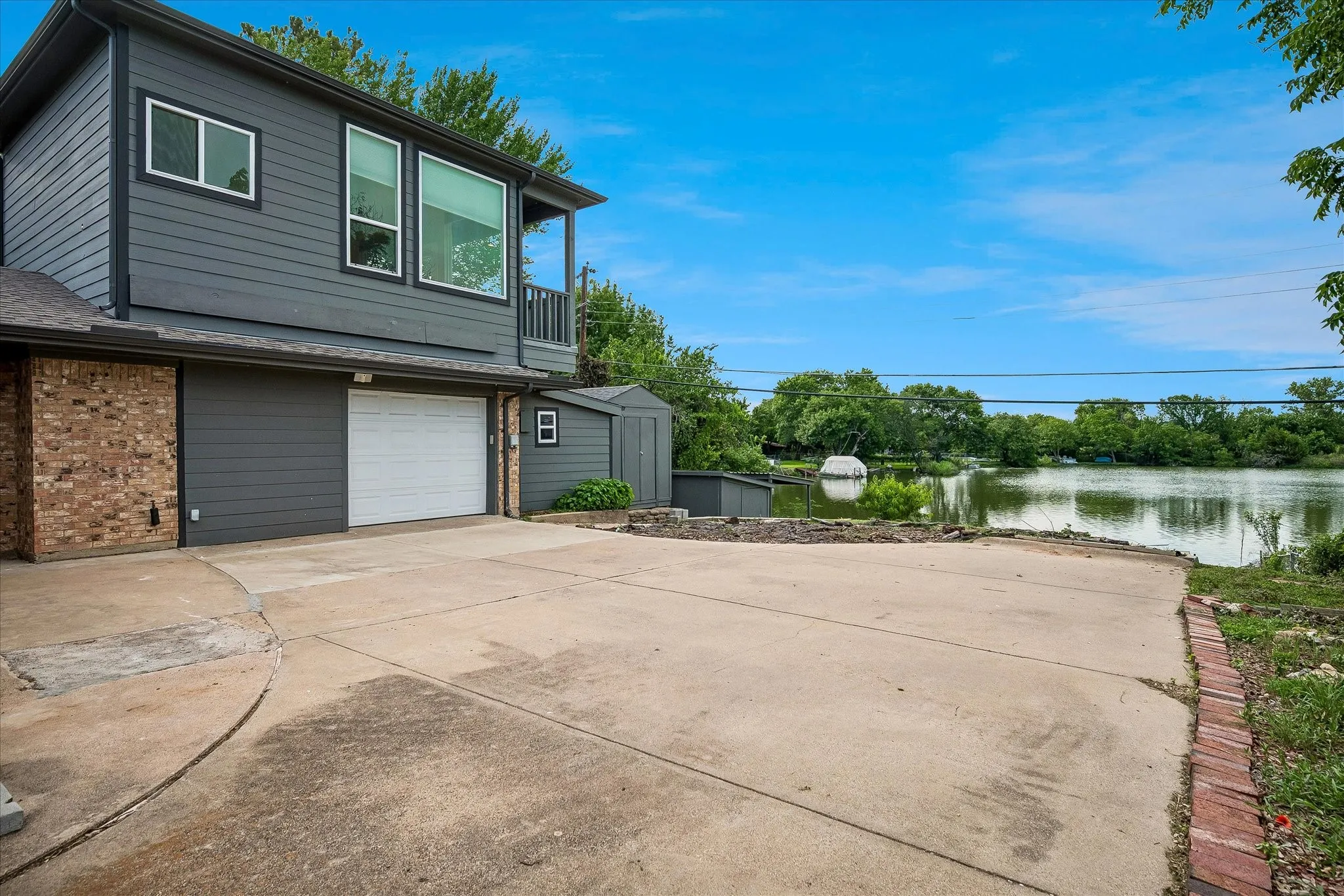 View of side entry garage, attached workshop, and view of lake in the background.