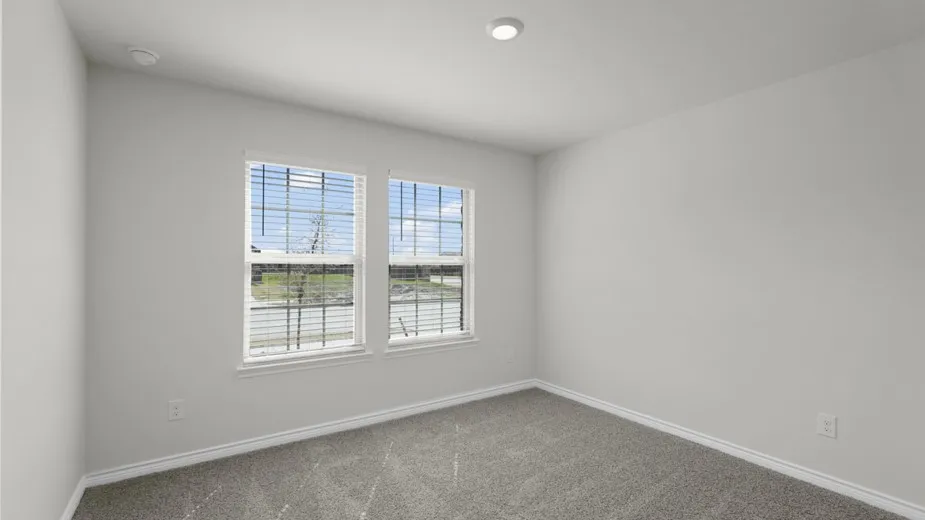 Light gray carpeted room with dual windows featuring white blinds, white trim, and a recessed ceiling light