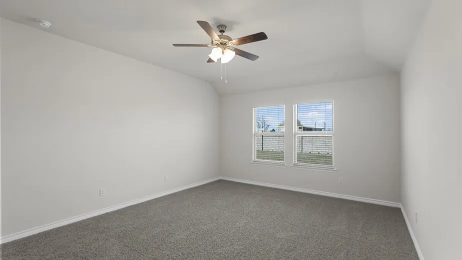 Spacious room featuring neutral carpeting, a ceiling fan with light fixture, and two windows equipped with blinds