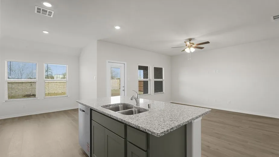 Kitchen island with integrated double basin sink, granite countertop, and dark cabinetry