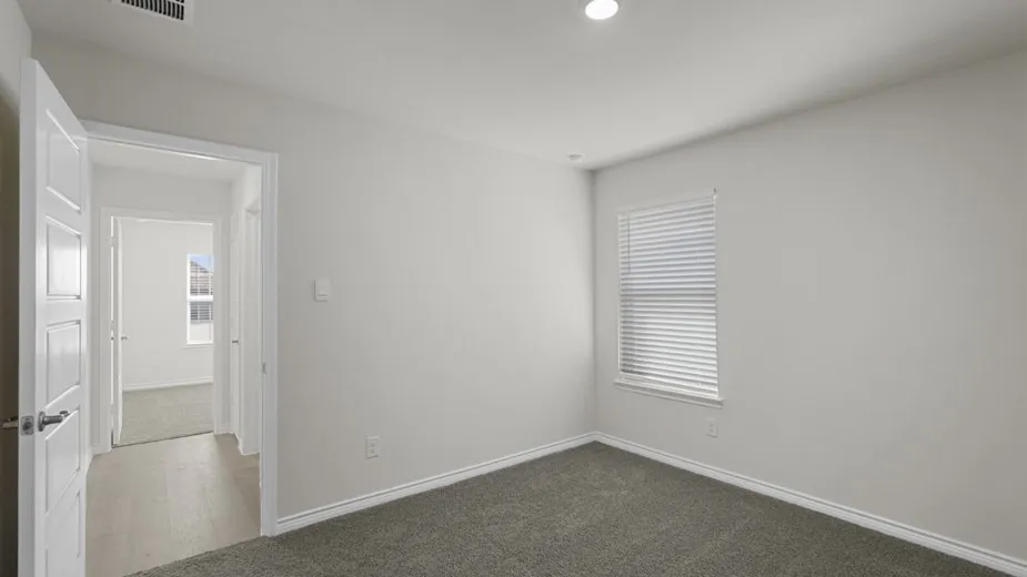 Interior room with light gray walls, gray carpet flooring, and a white trim baseboard
