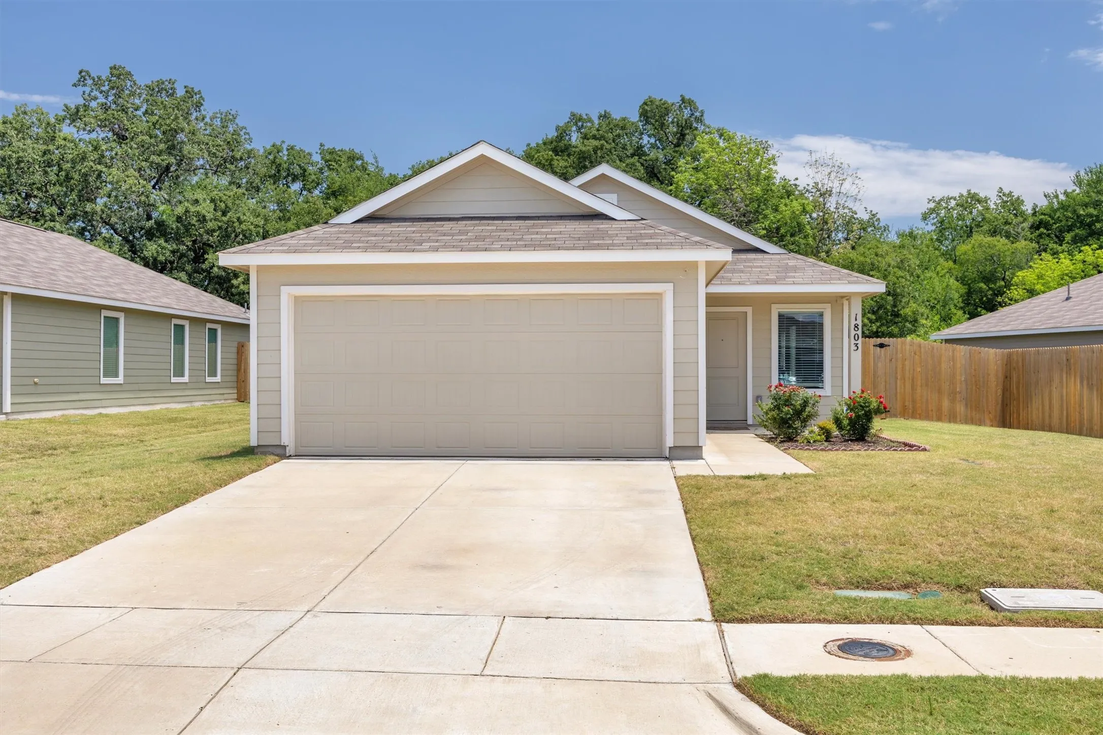 Single-story residence featuring a two-car garage, concrete driveway, and light-colored siding