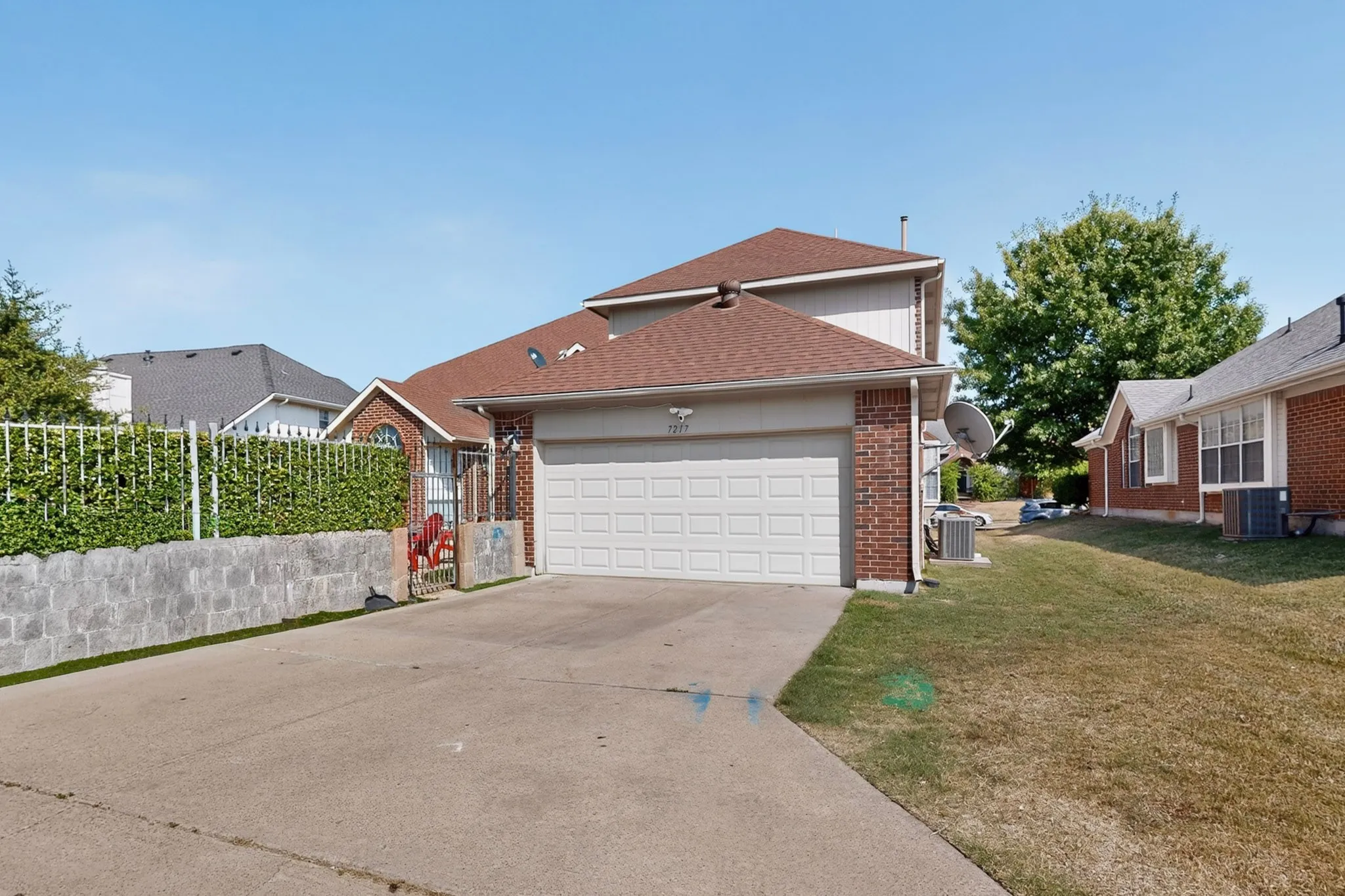 Front exterior showcasing a two-car garage, red brick accents, and a concrete driveway