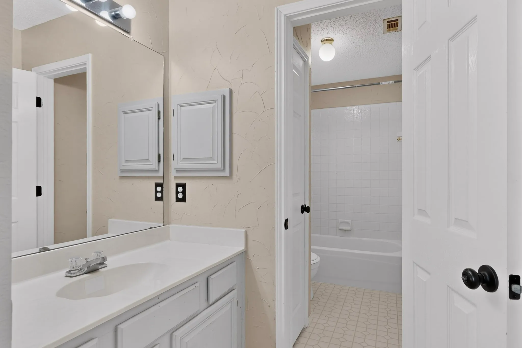 Bathroom vanity featuring a white countertop with integrated sink, chrome faucet, and white cabinetry