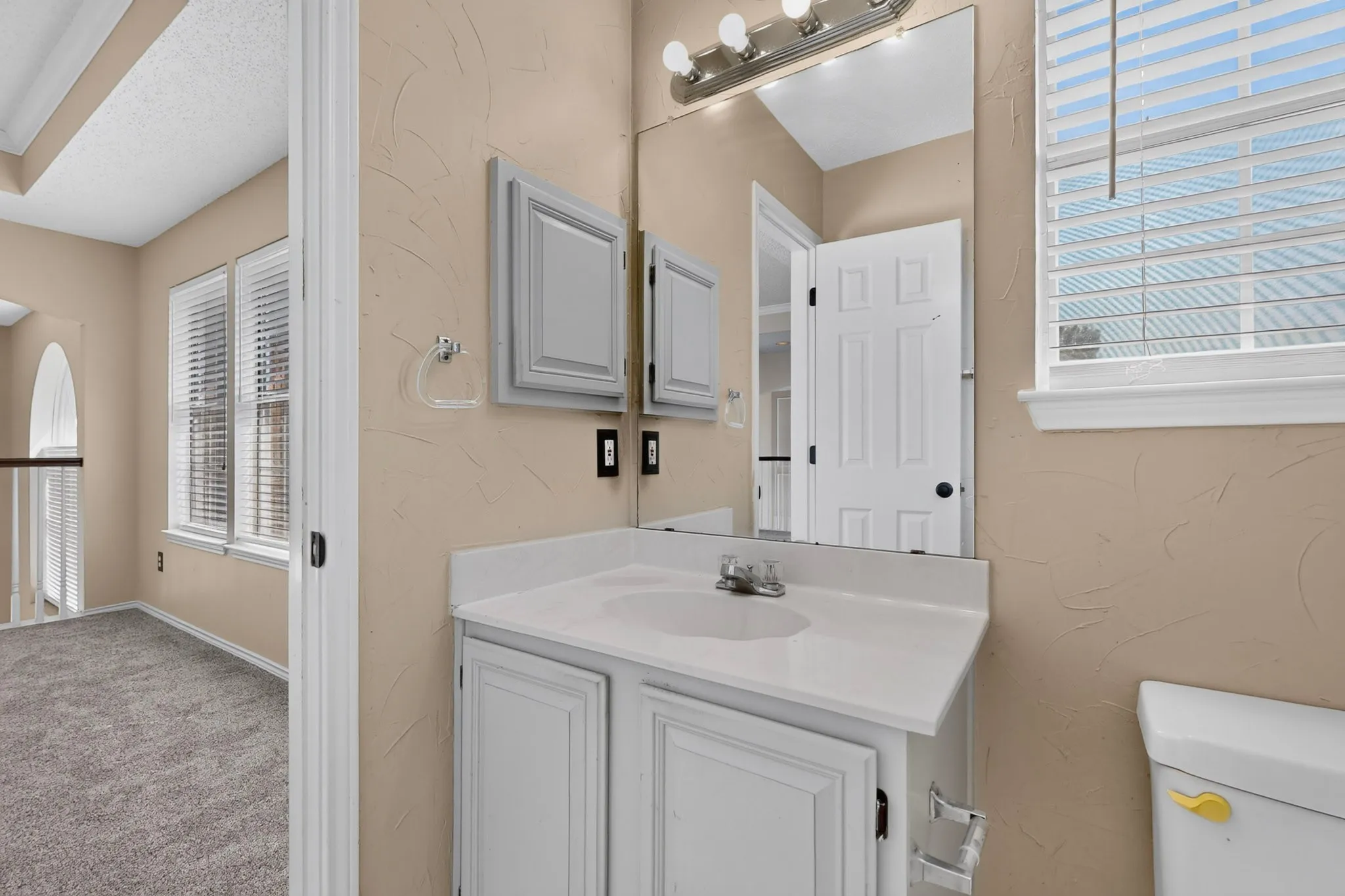 Bathroom vanity with light gray cabinetry, white countertop, and integrated sink