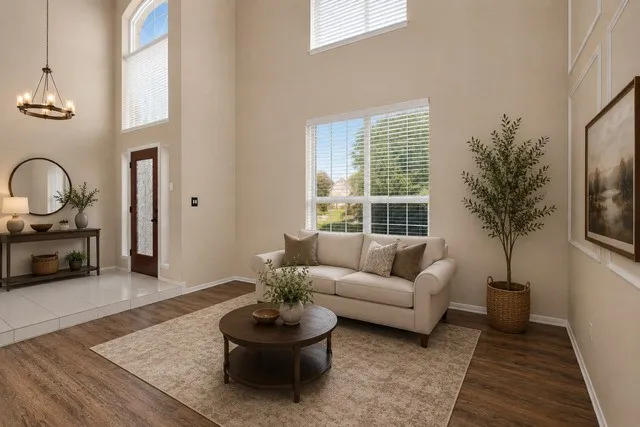Staged Soaring two-story foyer with abundant natural light from multiple windows and glass doors, complemented by a pendant light fixture