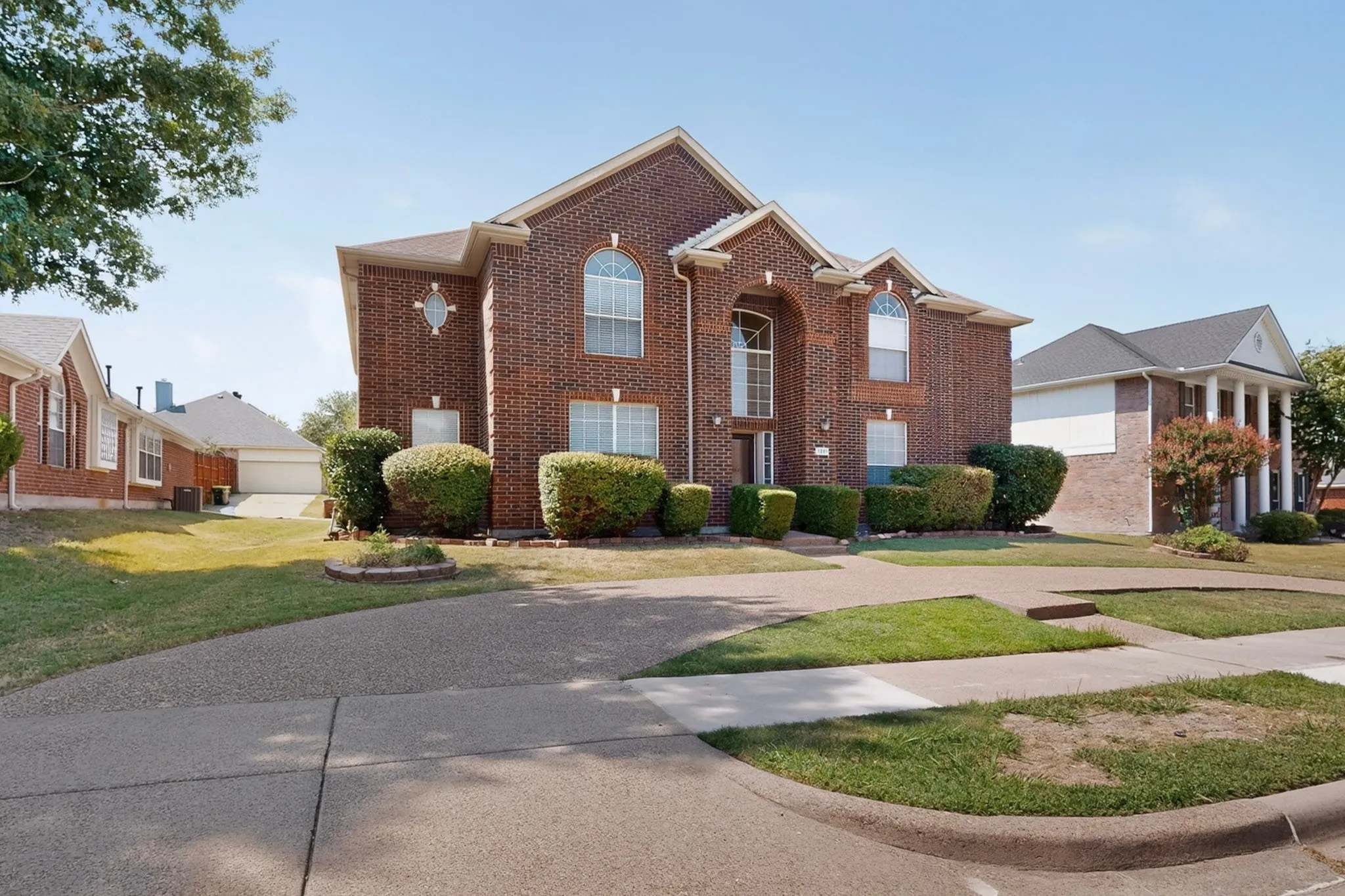 Brick two-story residence featuring an arched portico entry with an upper arched window