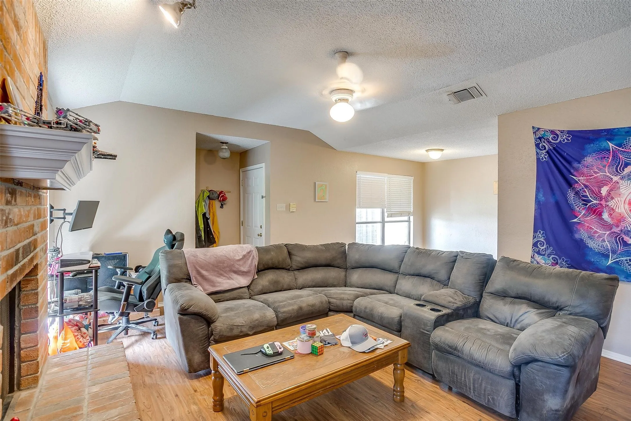 Living room featuring medium-toned wood-like flooring, sloped high ceiling and windows for natural lighting.