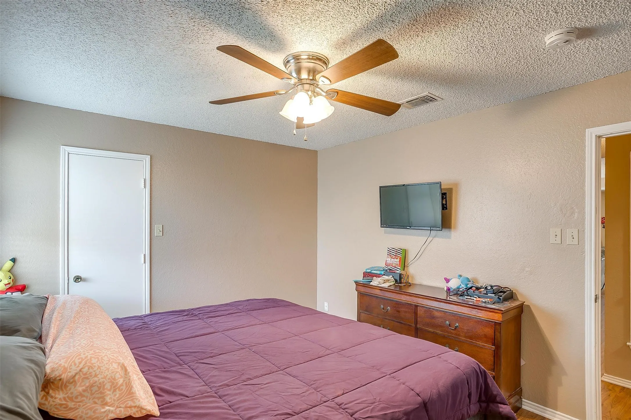 Bedroom featuring a warm neutral color palette, white interior doors and door frames, and integrated multi-bulb glass lights with frosted light covers.
