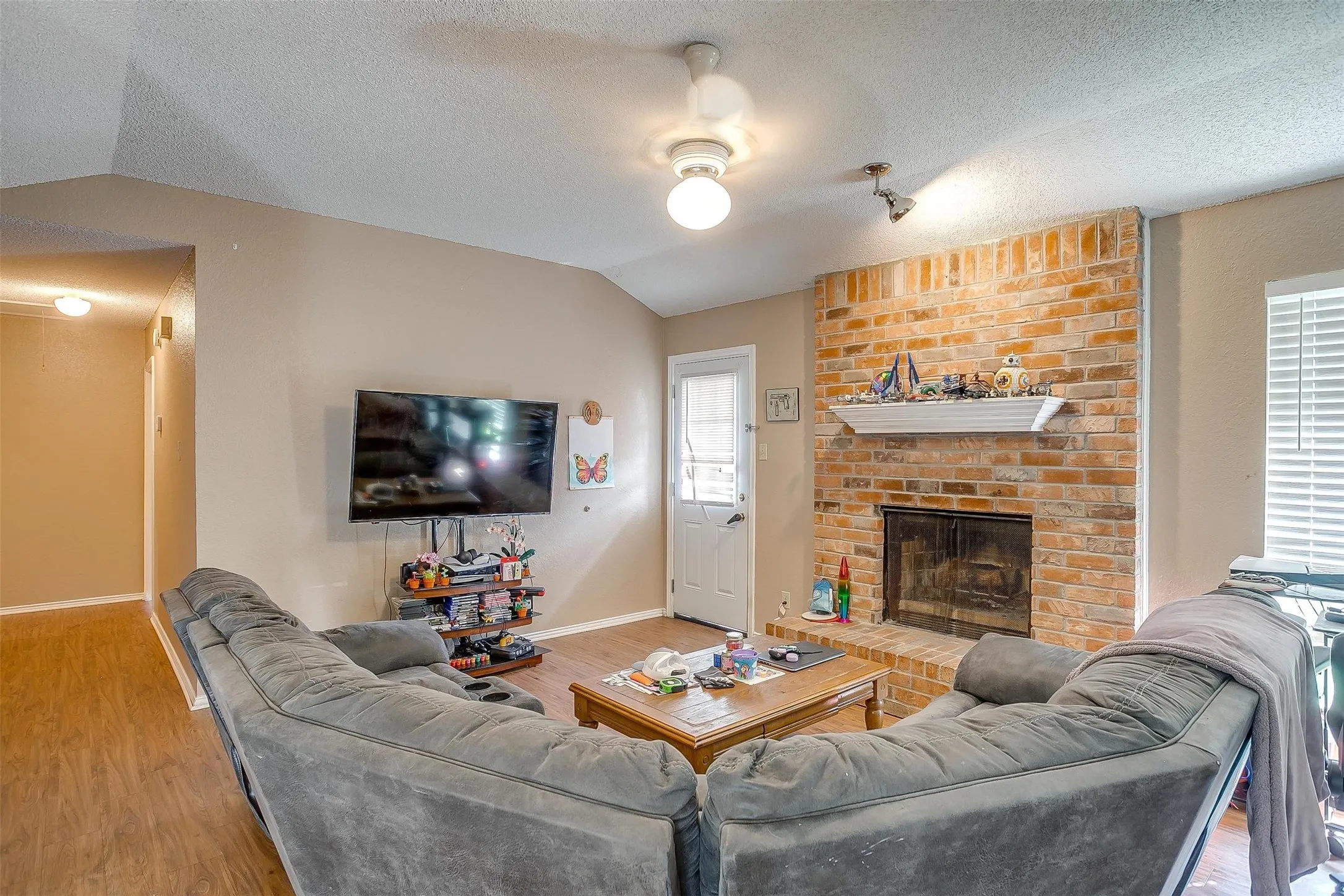 Living room featuring warm flooring, neutral color paint and a white exterior door to backyard.