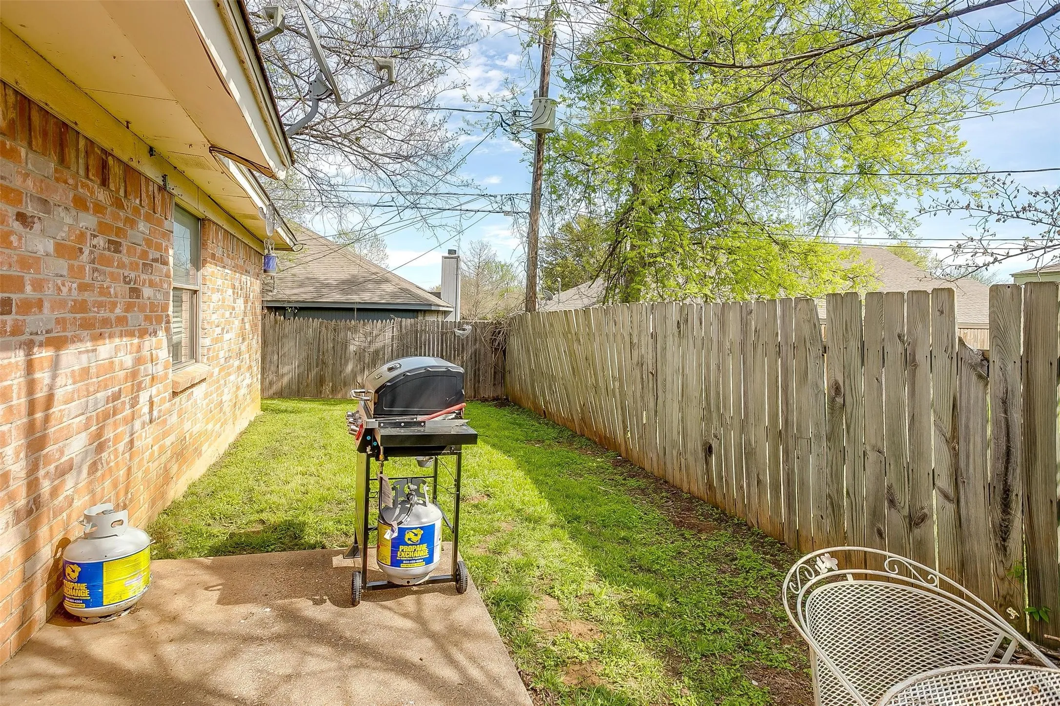 Side yard featuring wooden privacy fence and concrete patio for sitting area.