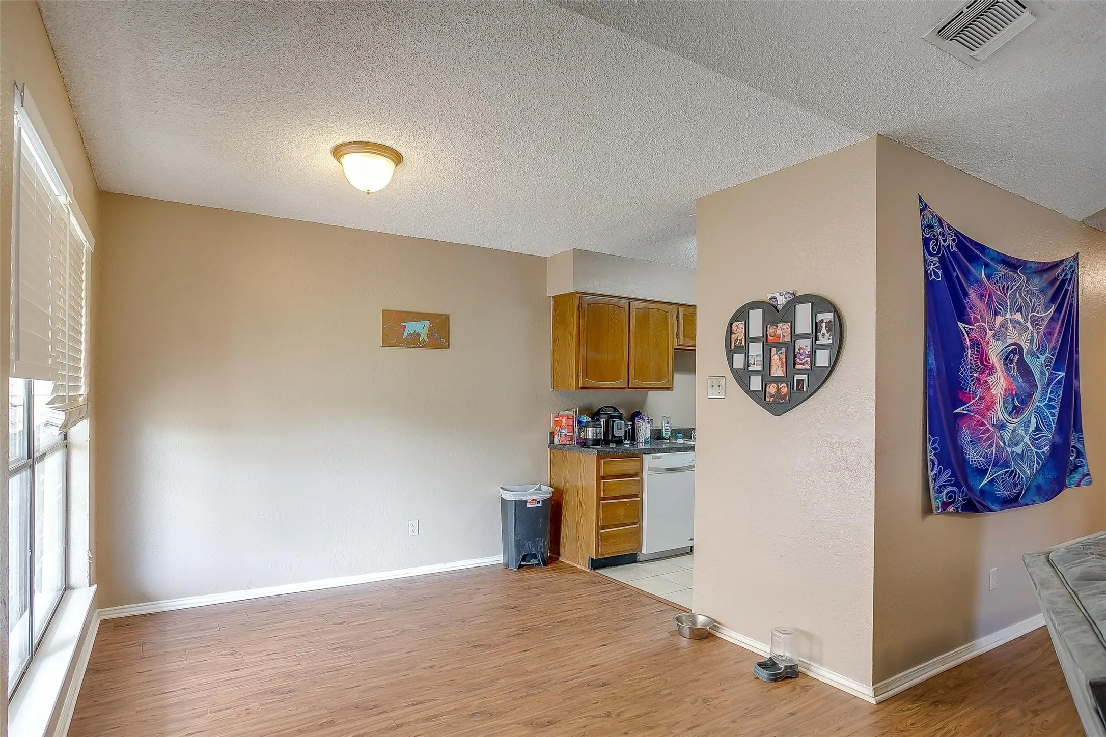 Dining area featuring wood-style flooring throughout dining area, neutral color paint with crisp white baseboards and window trim, and a flush-mount dome light fixture with frosted glass shade.