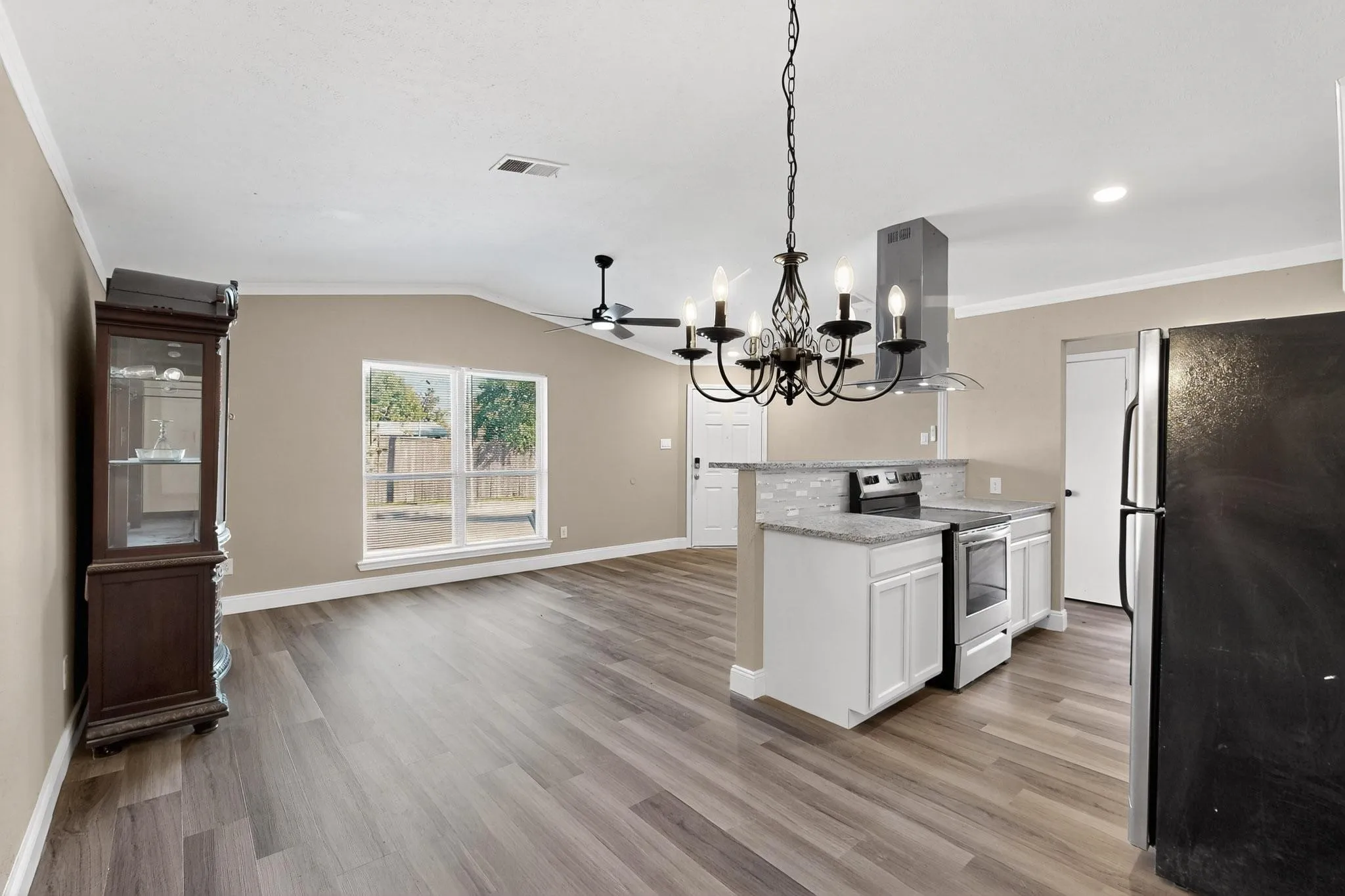 Kitchen featuring appliances with stainless steel finishes, white cabinetry, a chandelier, open floor plan, and light stone countertops