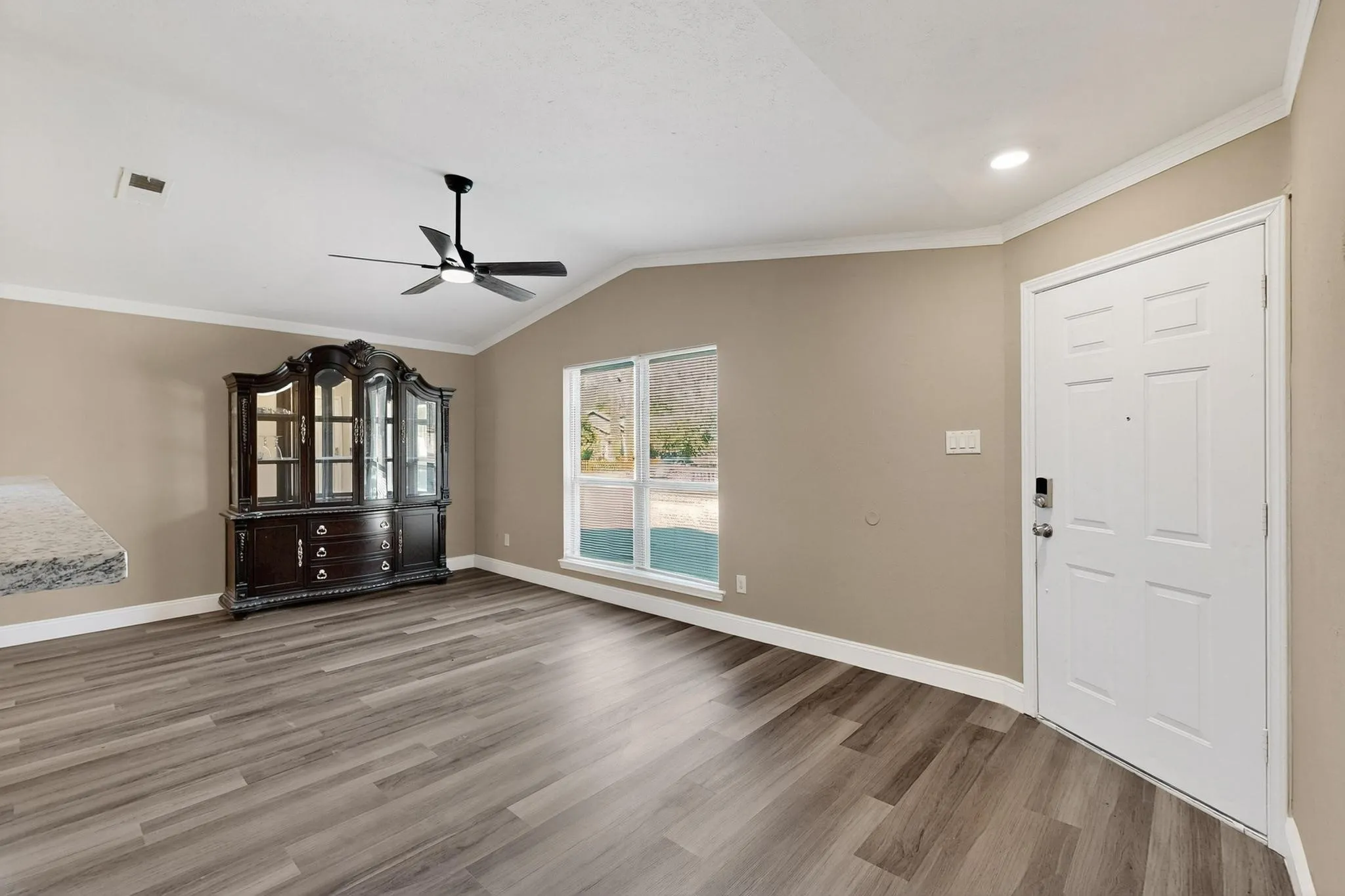 Entrance foyer featuring ornamental molding, vaulted ceiling, light wood-style floors, and a ceiling fan