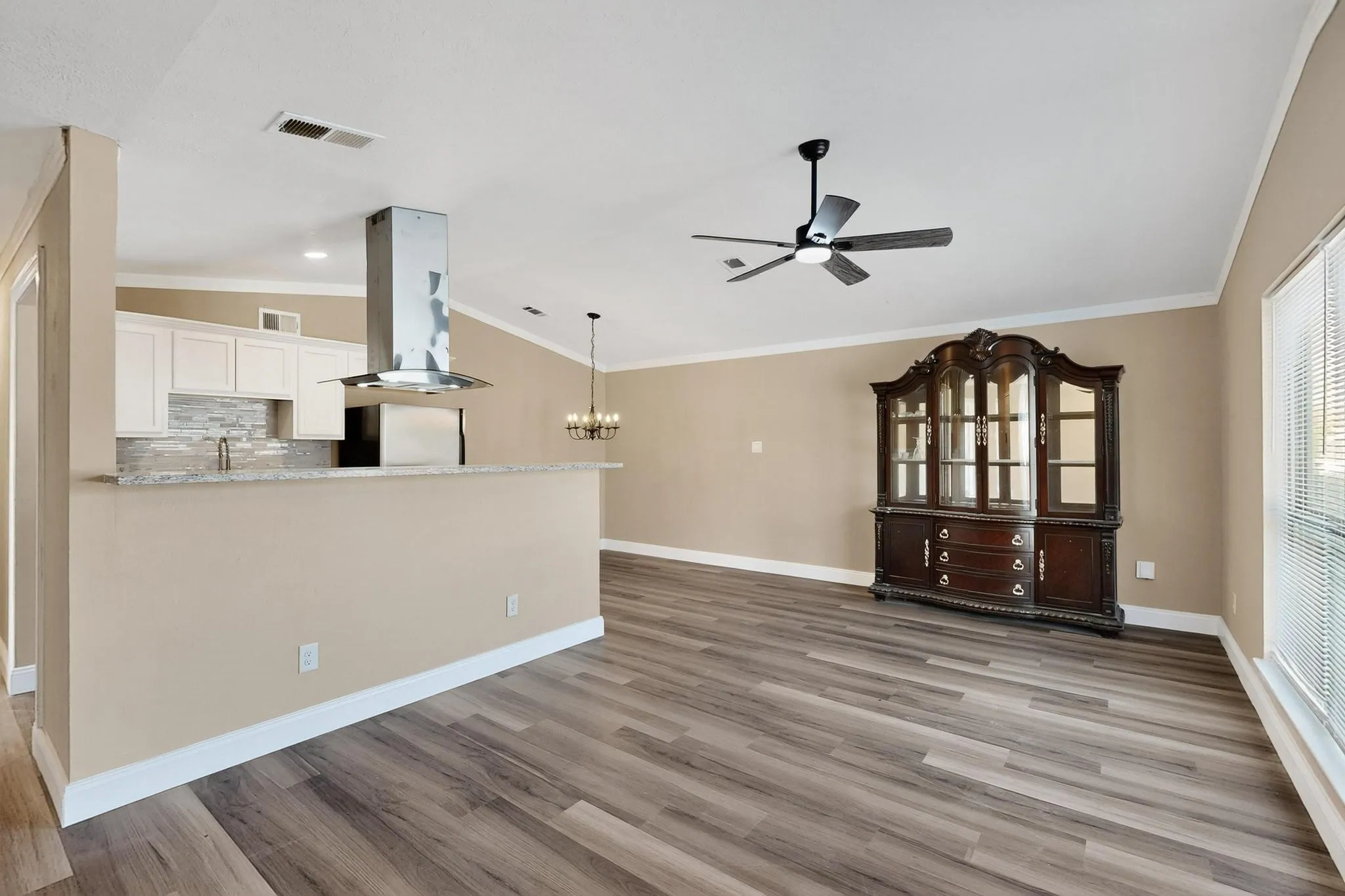 Unfurnished living room featuring light wood finished floors, ornamental molding, a chandelier, and ceiling fan