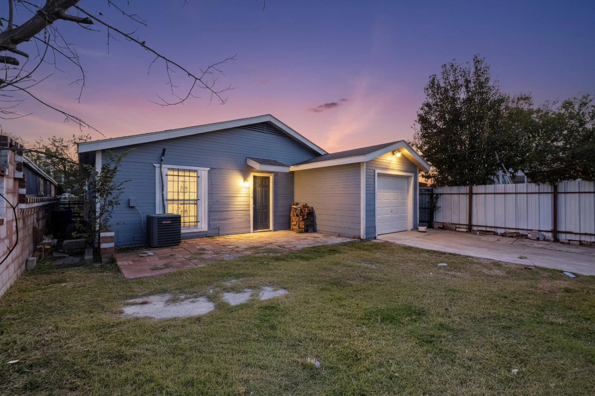 View of front of house with concrete driveway, a garage, and a patio area