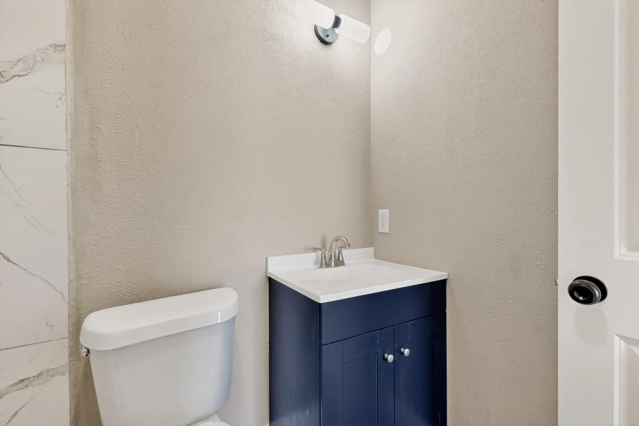 Half bath with vanity and a textured wall
