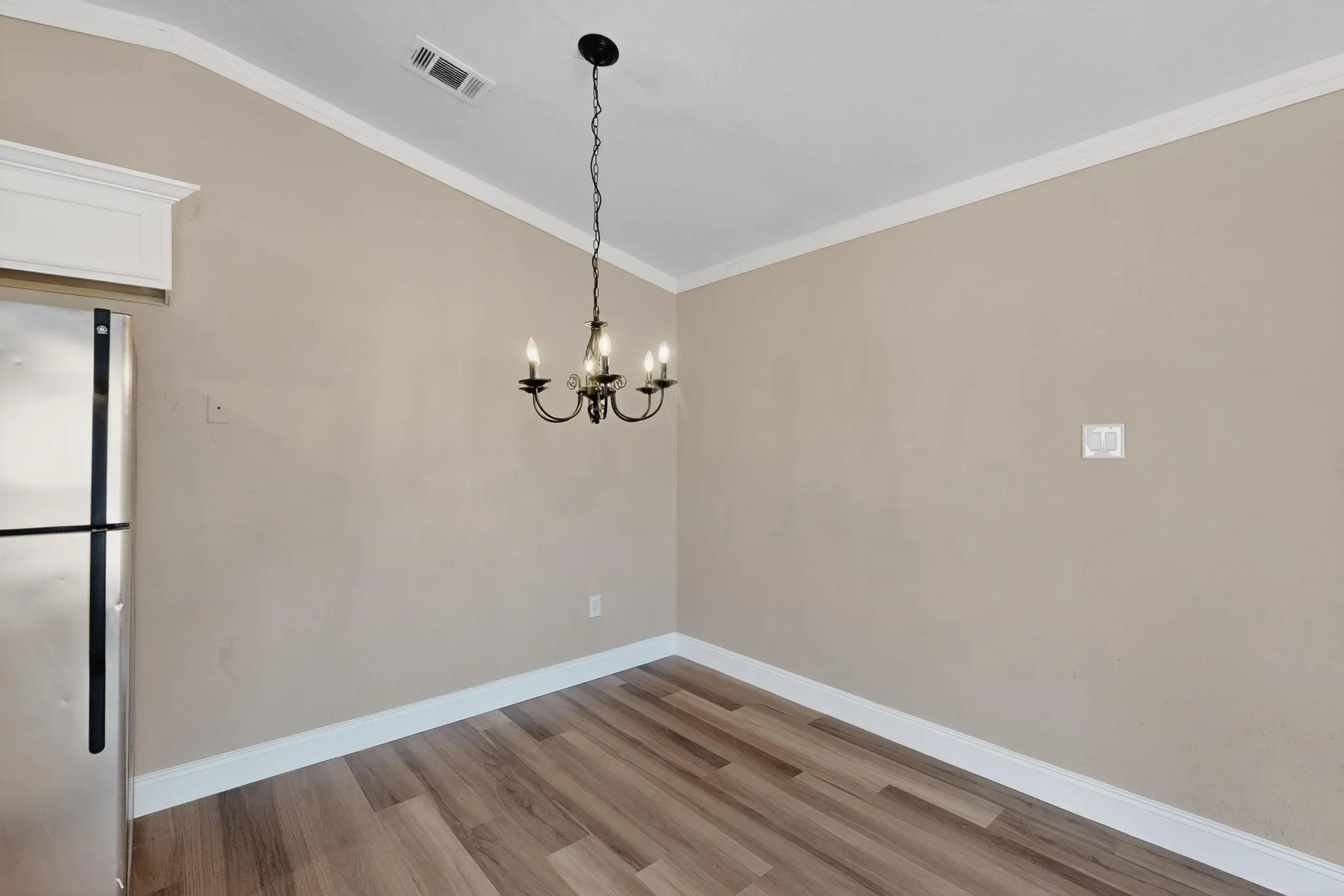 Unfurnished room featuring ornamental molding, light wood finished floors, and a chandelier