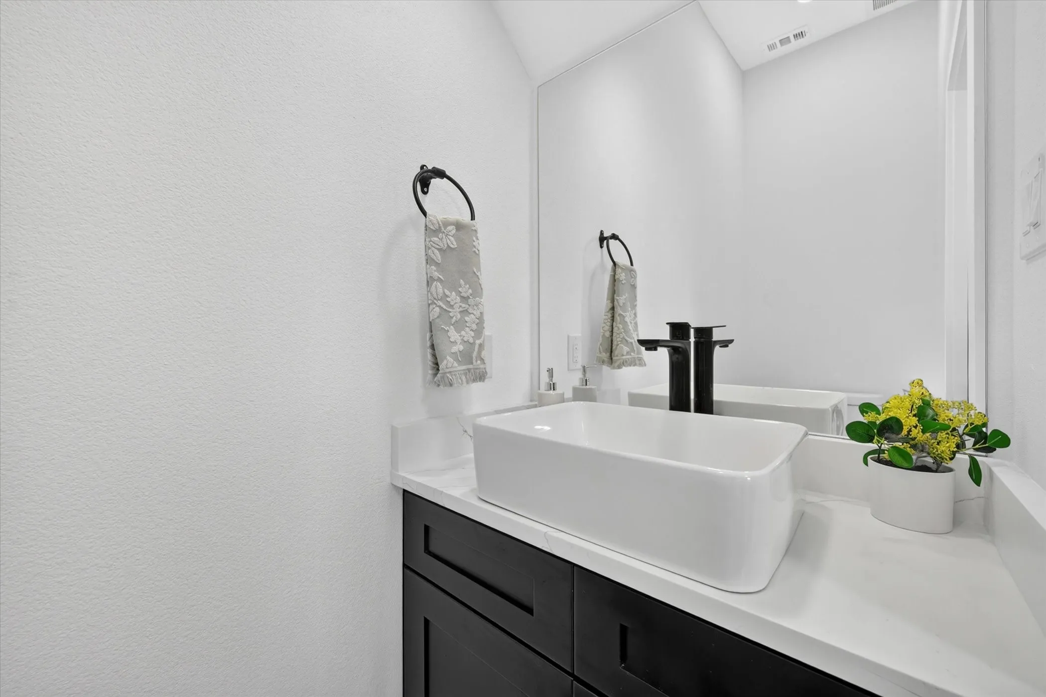 Modern vanity featuring a rectangular vessel sink, matte black wall-mounted faucet, dark wood-finish cabinetry, and a white countertop