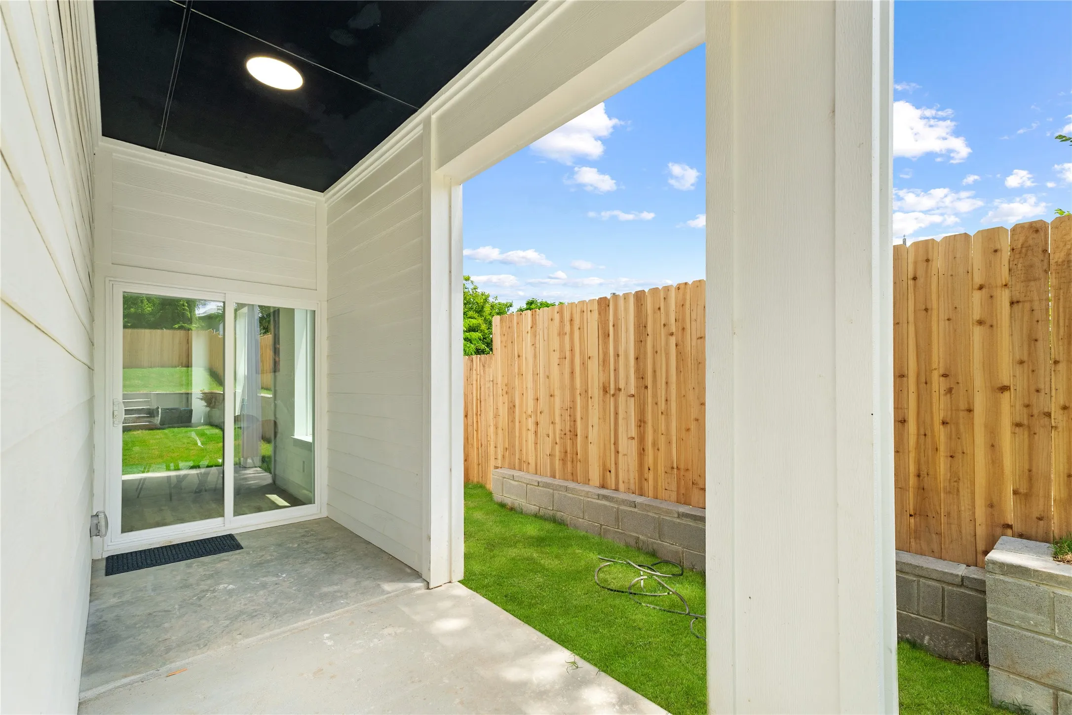 Covered patio featuring a black ceiling with recessed lighting, concrete flooring, and white horizontal siding