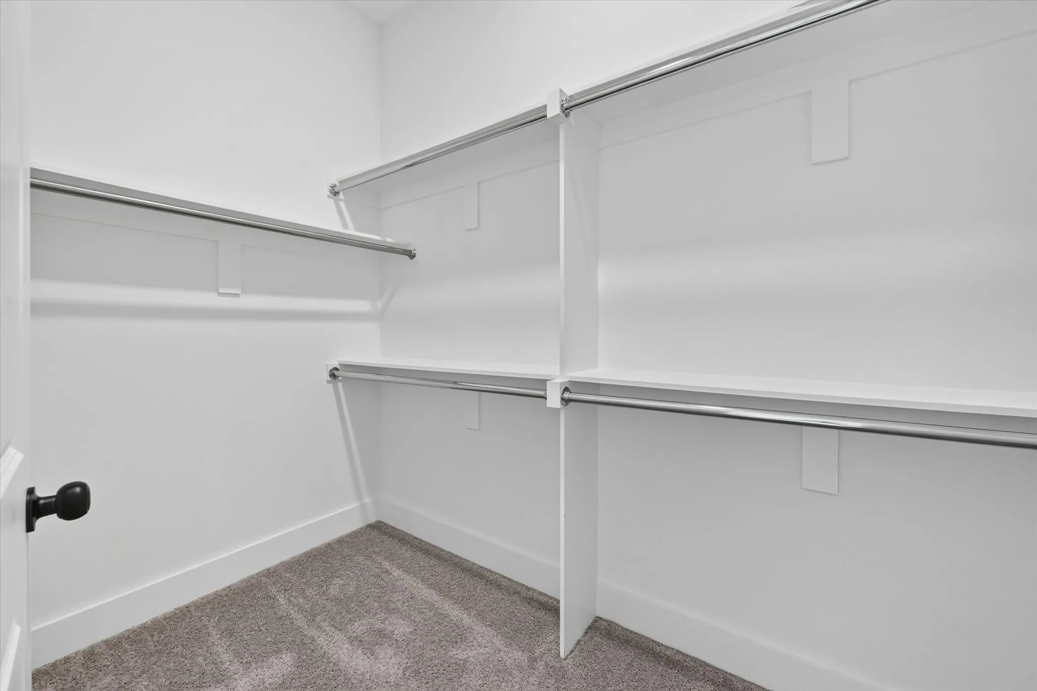 White walk-in closet featuring multiple shelving units and chrome hanging rods