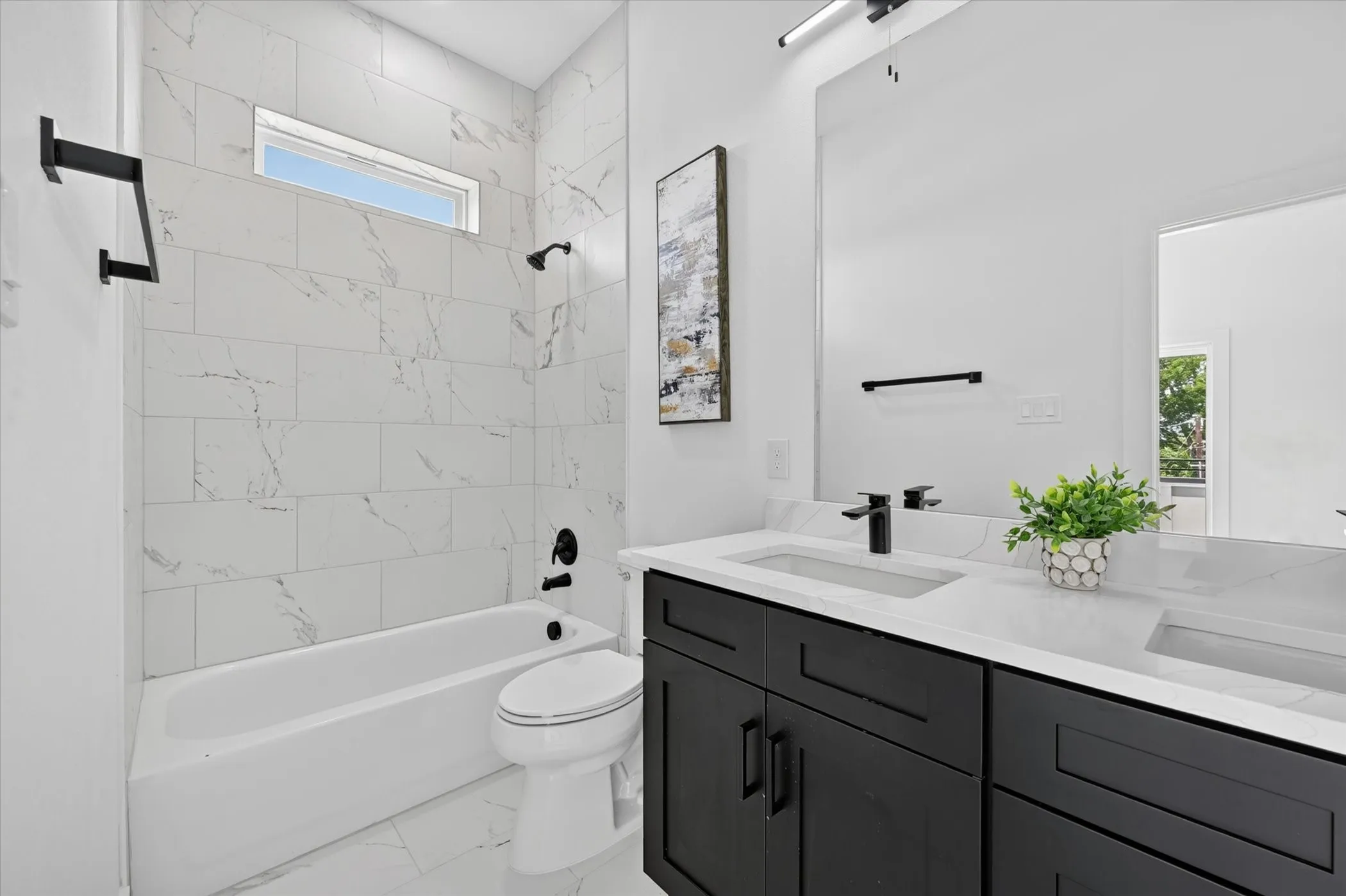 Modern bathroom featuring a double vanity with dark cabinetry, white countertops, and integrated rectangular sinks
